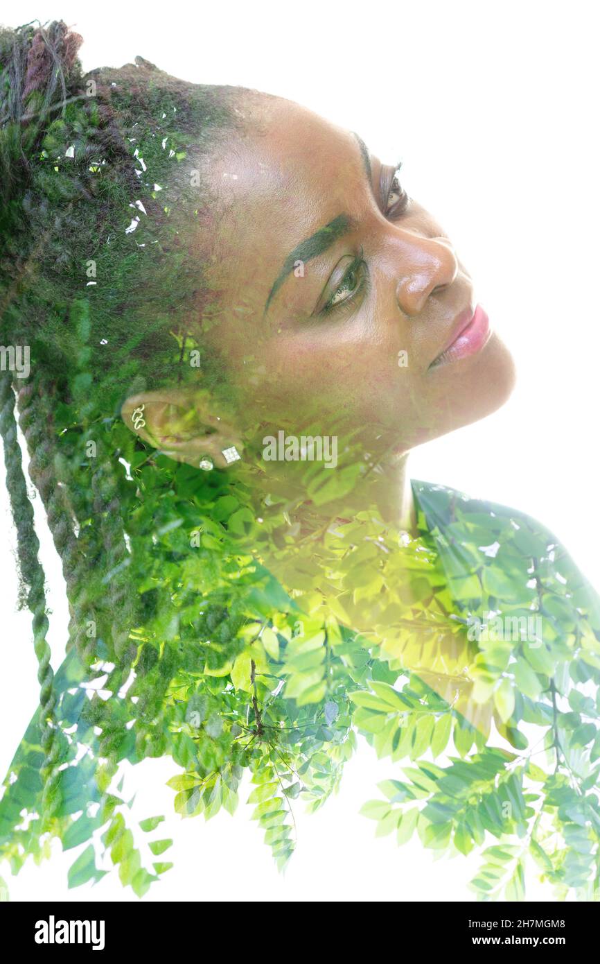 Un ritratto di una donna afroamericana combinata con un'immagine di foglie verdi in una tecnica a doppia esposizione. Foto Stock