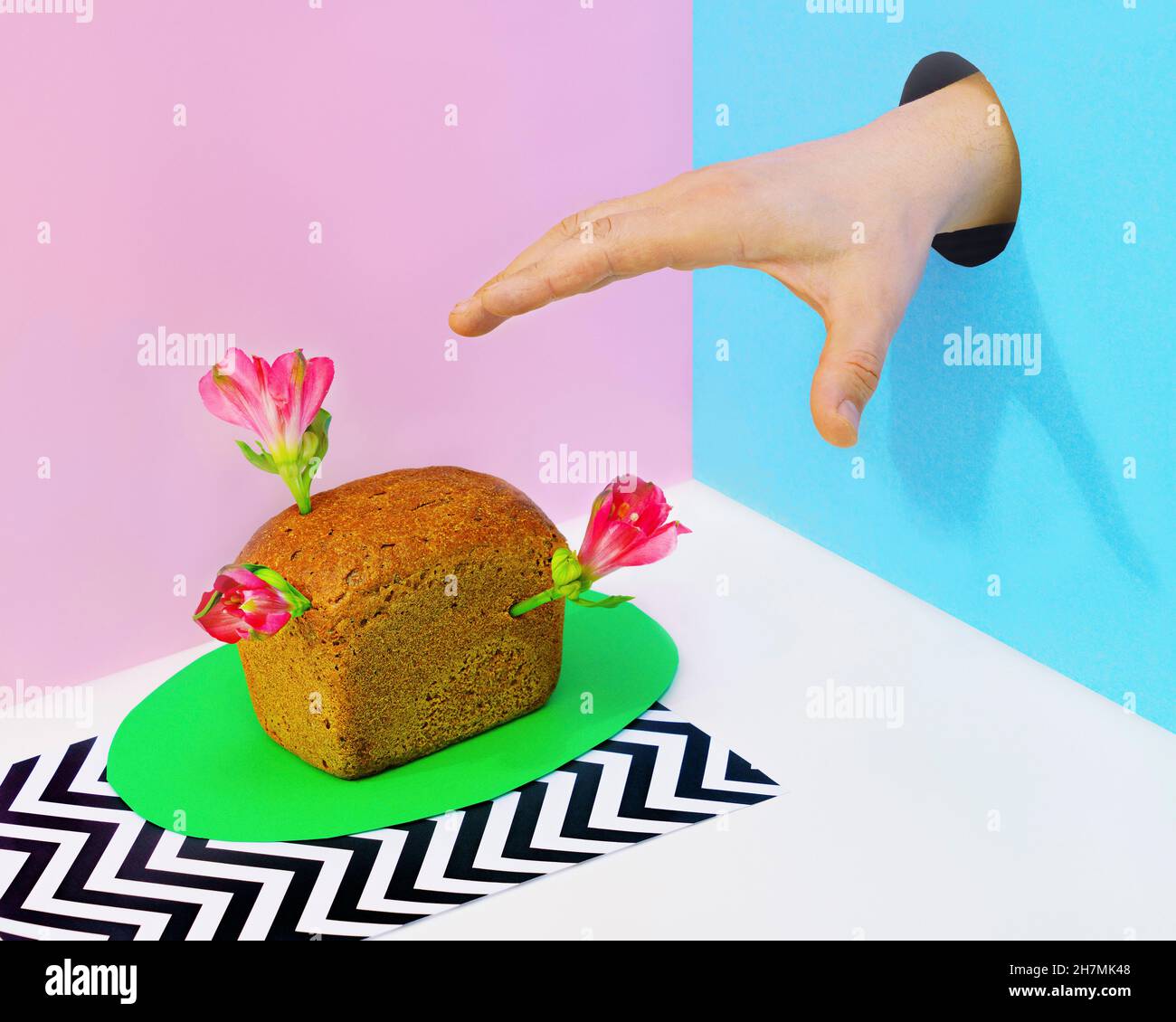 Mano nel foro che raggiunge per mini pagnotta di pane con fiori Foto Stock