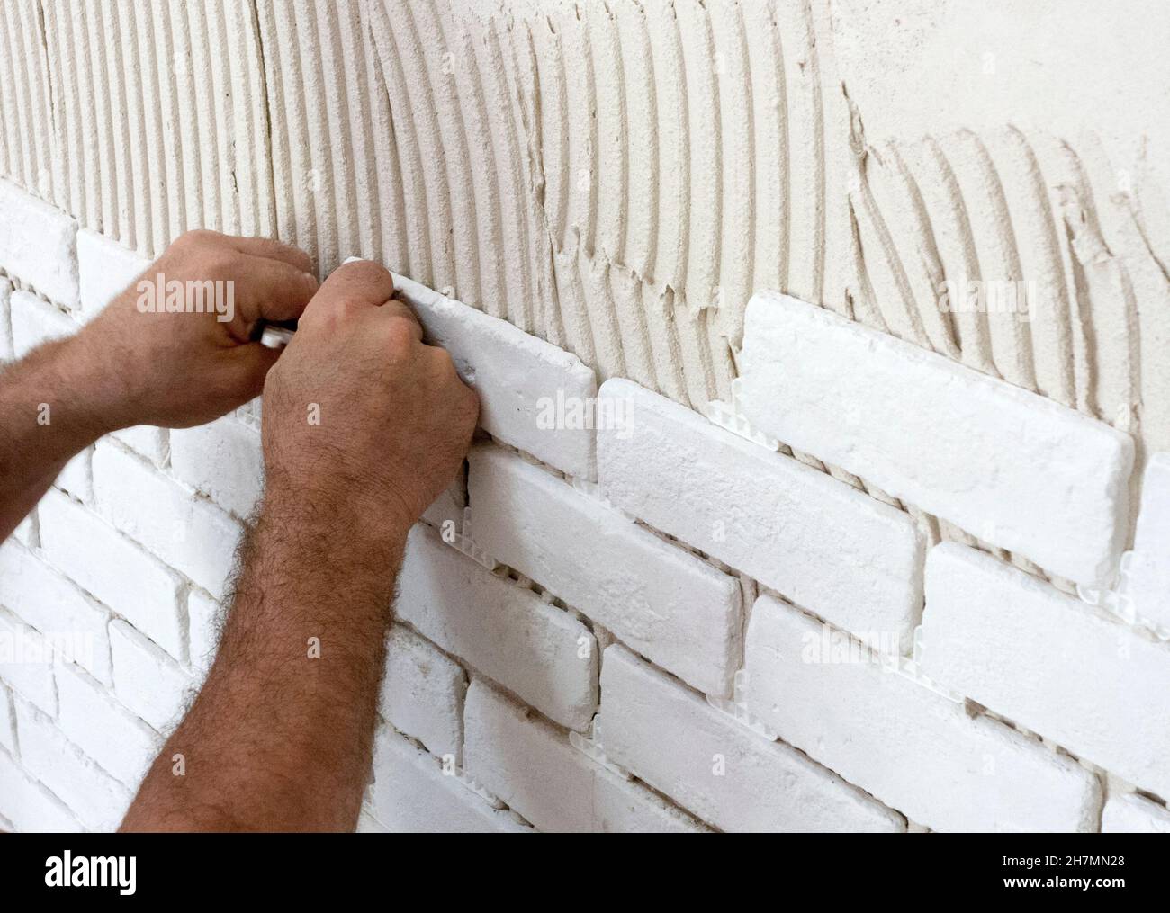 Lavoratore che mette mattoni decorativi sul muro Foto Stock