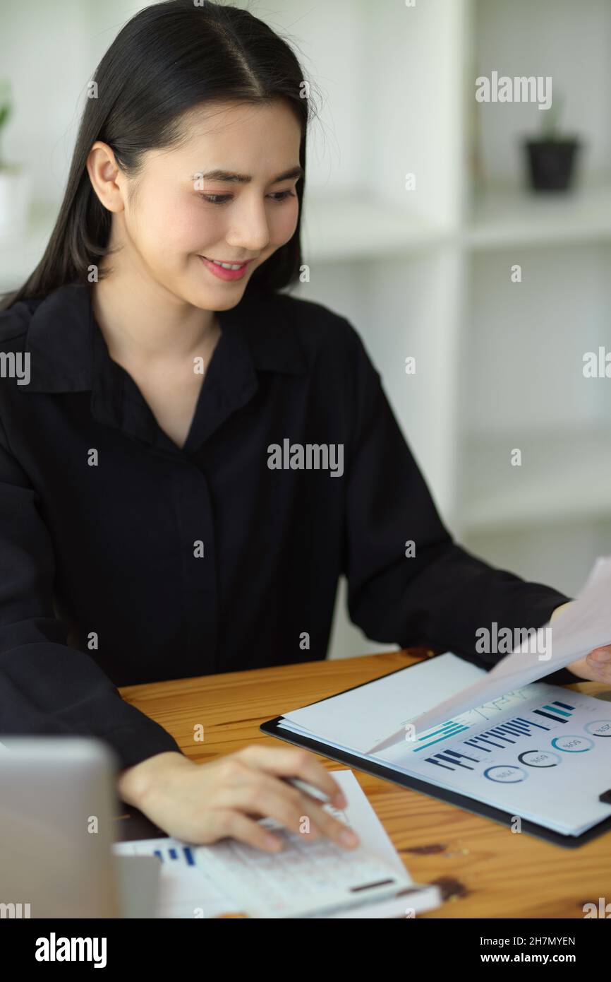 Un consulente finanziario femminile bello sta calcolando e prevedendo un preventivo per un nuovo commercio. Foto Stock