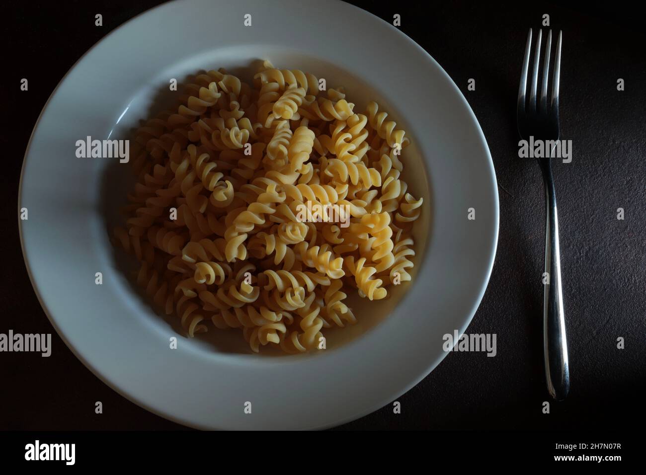 Pasta fresca fusilli su sfondo scuro. Direttamente sopra. Foto Stock