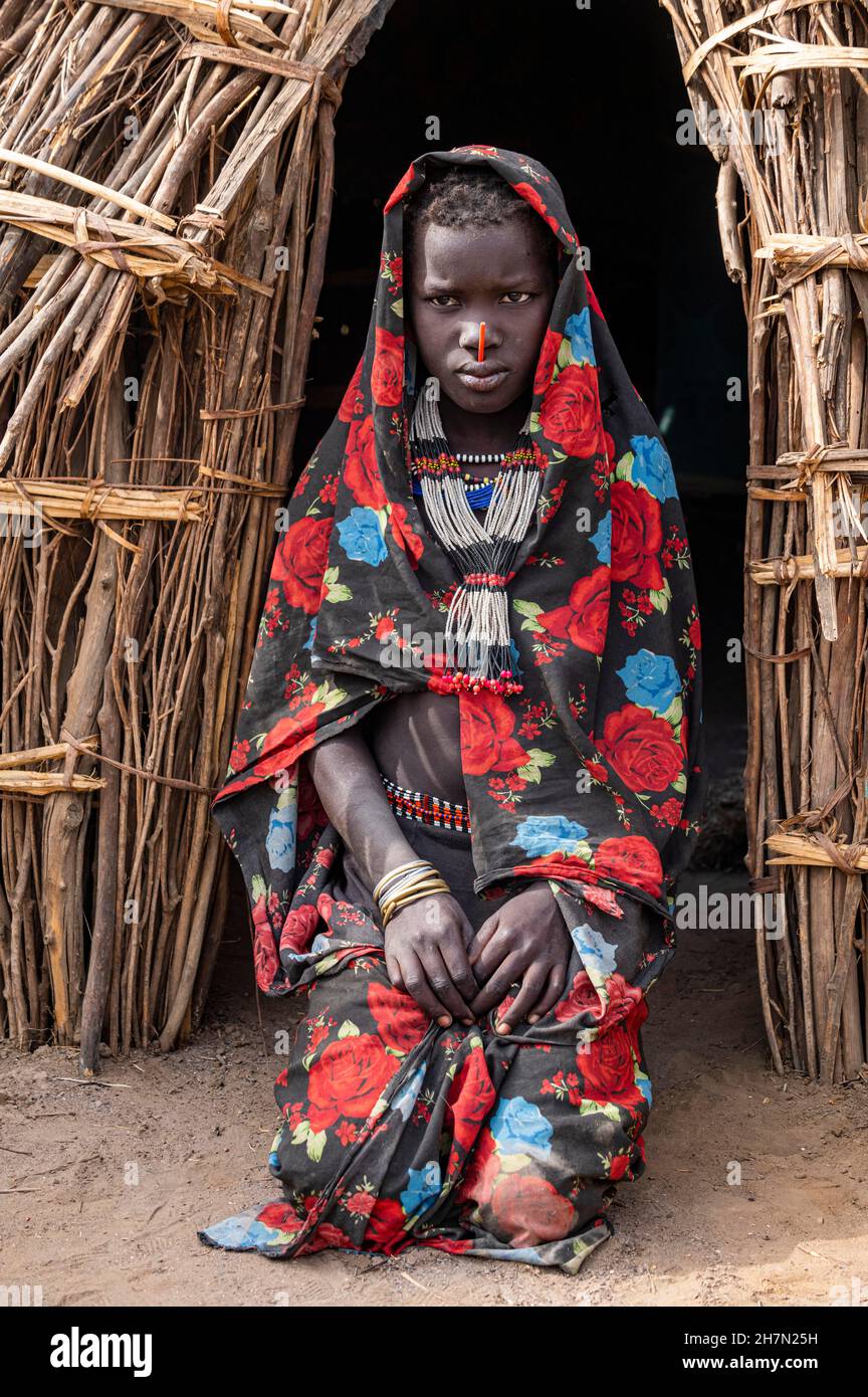 Bambino vestito tradizionale della tribù Jiye seduto nella sua capanna, Eastern Equatoria state, South Sudan Foto Stock
