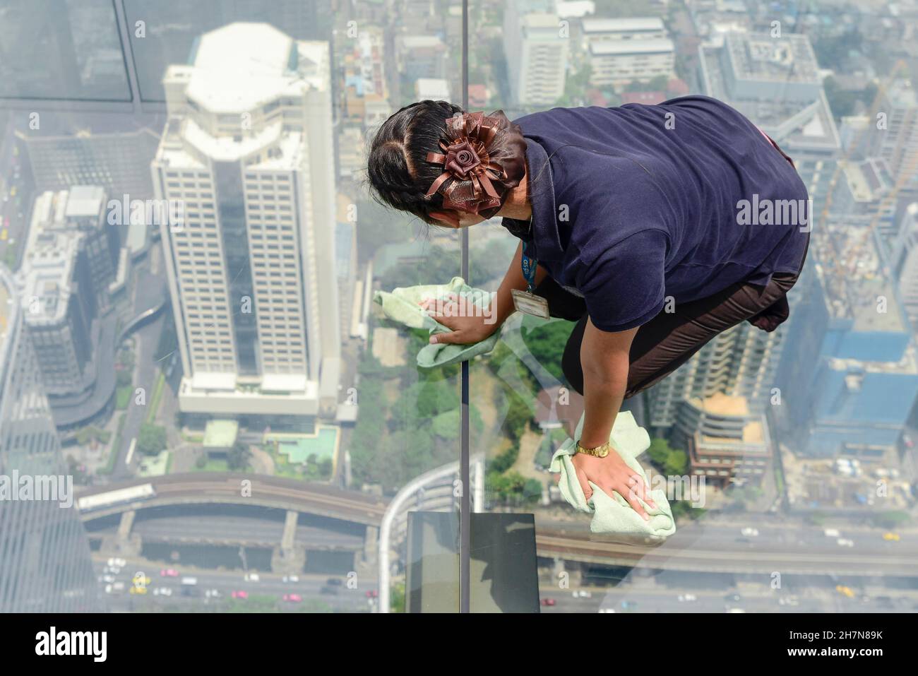 Donna pulizia pavimento in vetro della Maha Nakhon Tower, Bangkok, Thailandia Foto Stock
