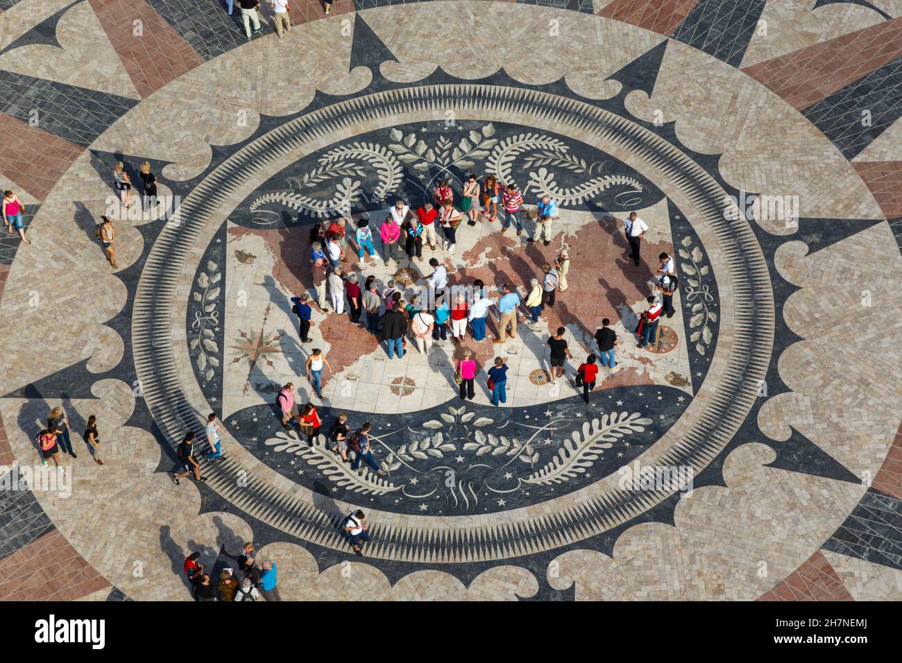 Lisbona, Portogallo. I turisti che esaminano la mappa del mondo e la bussola sorgono sul marciapiede dietro Padrao dos Descobrimentos, o Monumento alle scoperte. Foto Stock