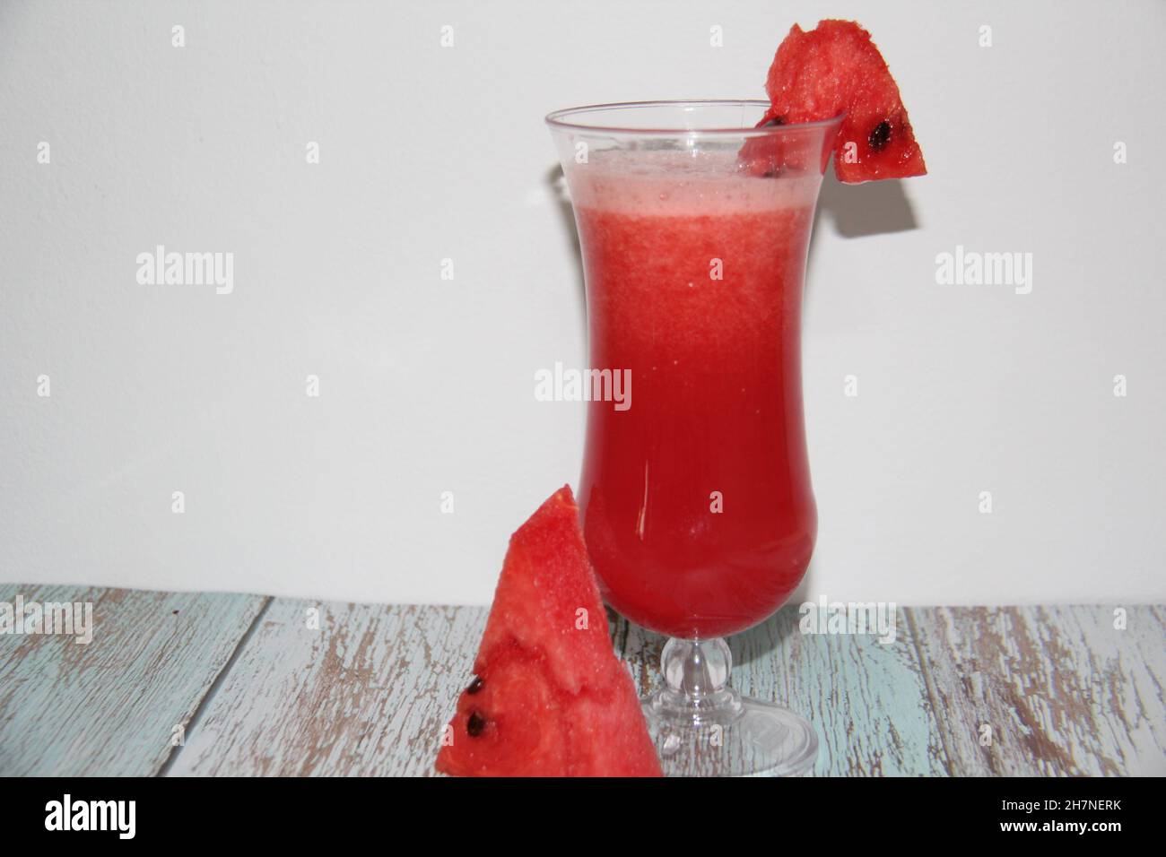 Succo di cocomero in una tazza di vetro trasparente su un vecchio tavolo di legno e lo sfondo bianco Vista dall'alto. Foto Stock