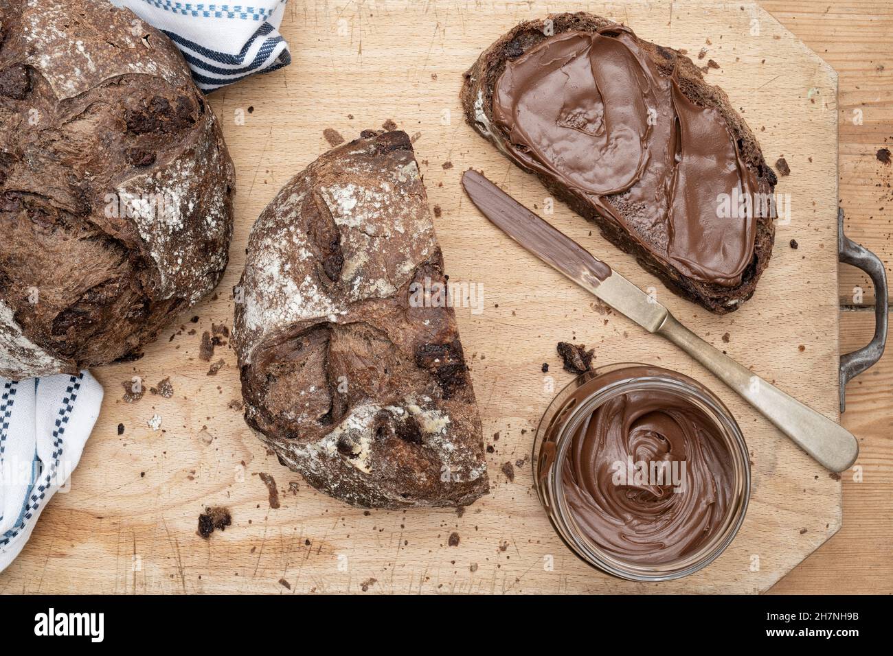 Pane al cioccolato a pasta di legno con nocciola al cioccolato spalmata su un asse di legno Foto Stock