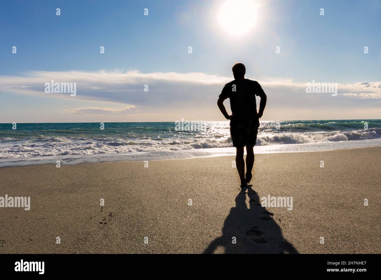 Silhouette di un uomo che cammina sulla spiaggia contro il mare Foto Stock