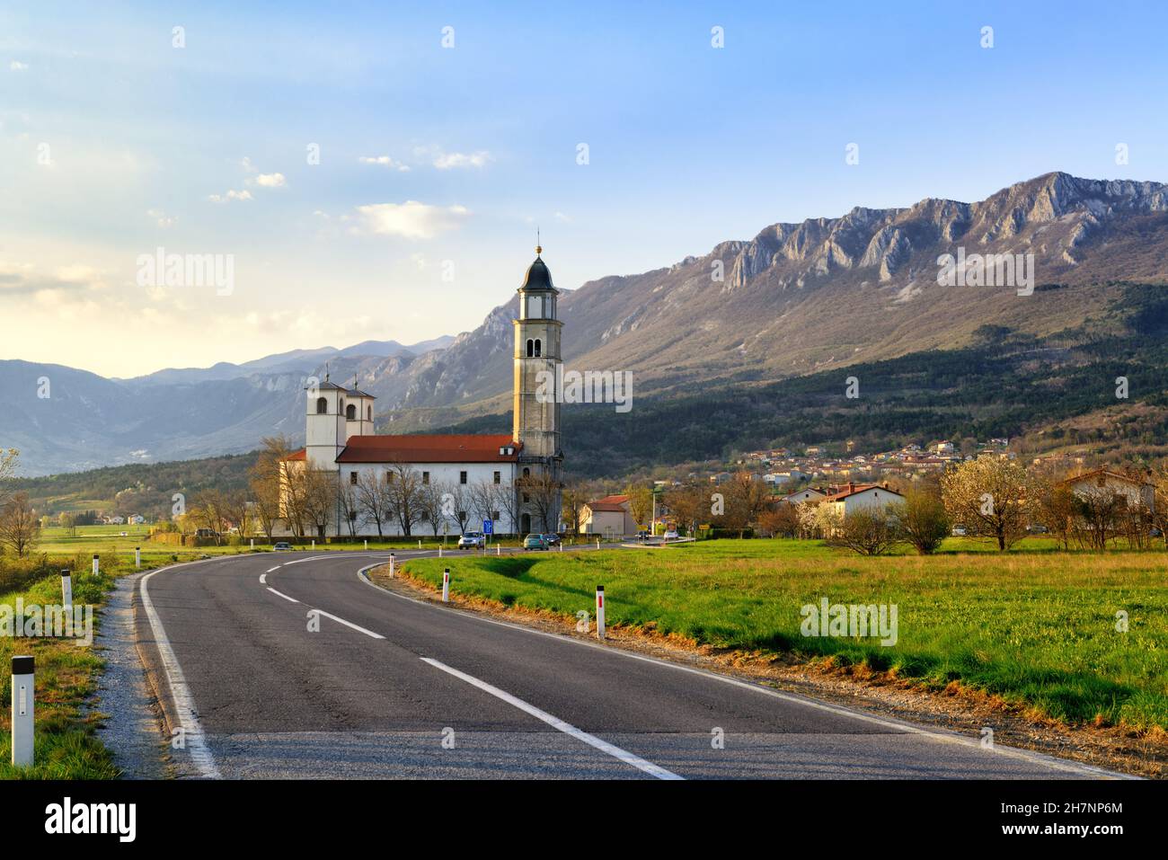 Bella serata paesaggio di campagna con strada, chiesa e montagne sullo sfondo Foto Stock
