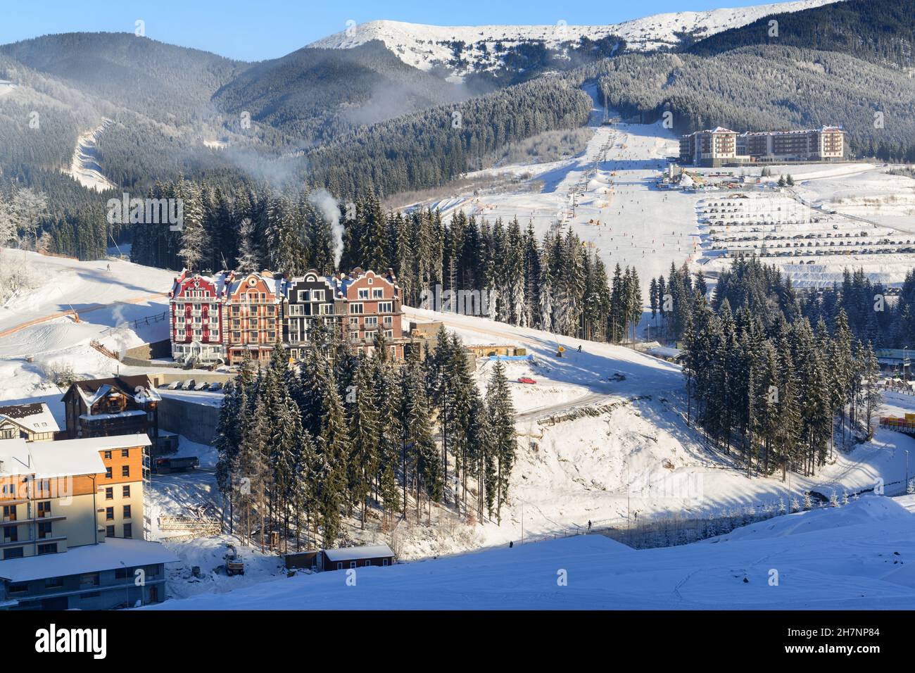 Splendida vista sulla località invernale con hotel e piste da sci circondati da montagne Foto Stock