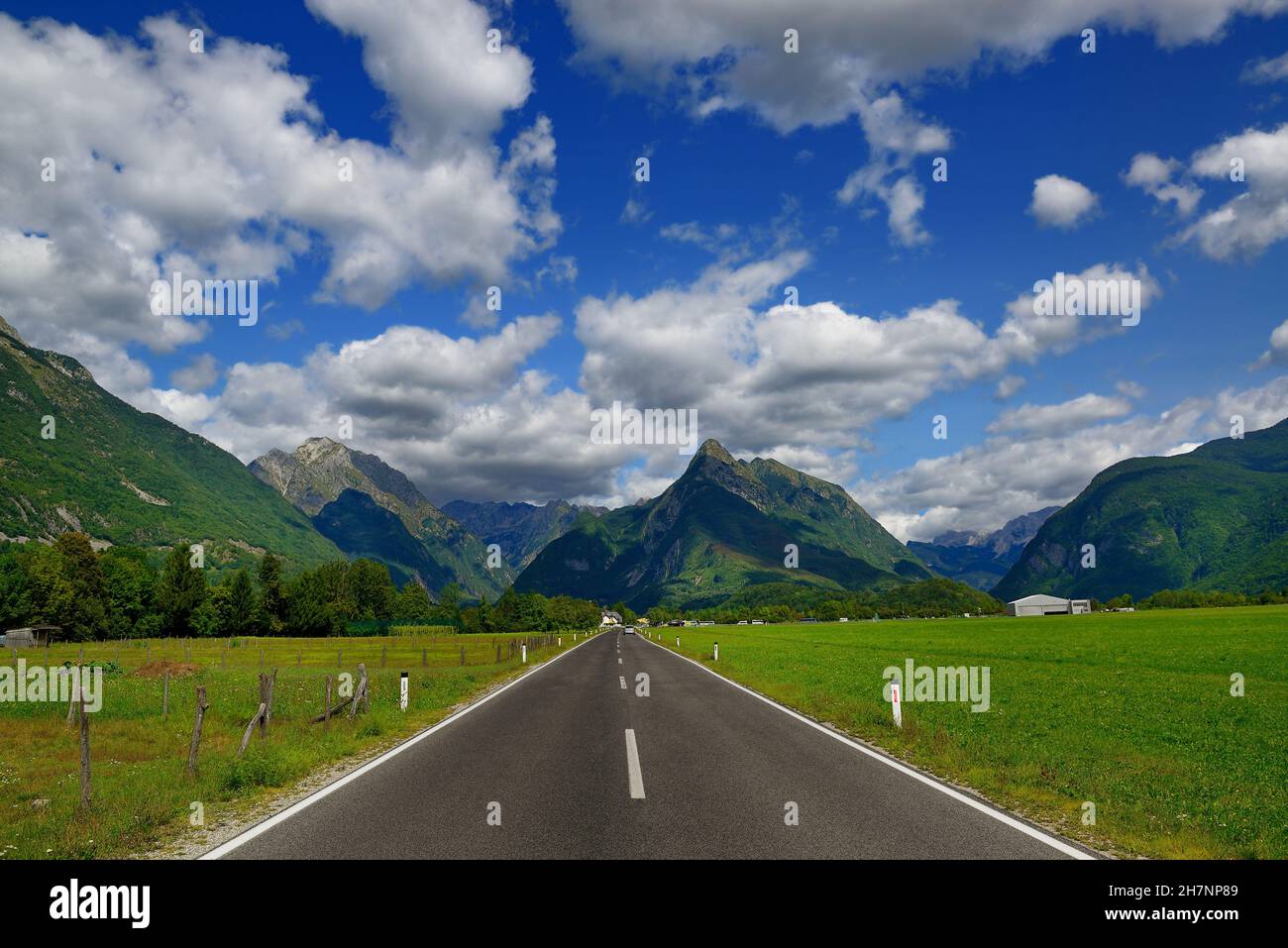 Strada asfaltata diritta nella splendida valle alpina in Slovenia con cielo blu profondo e montagne Foto Stock