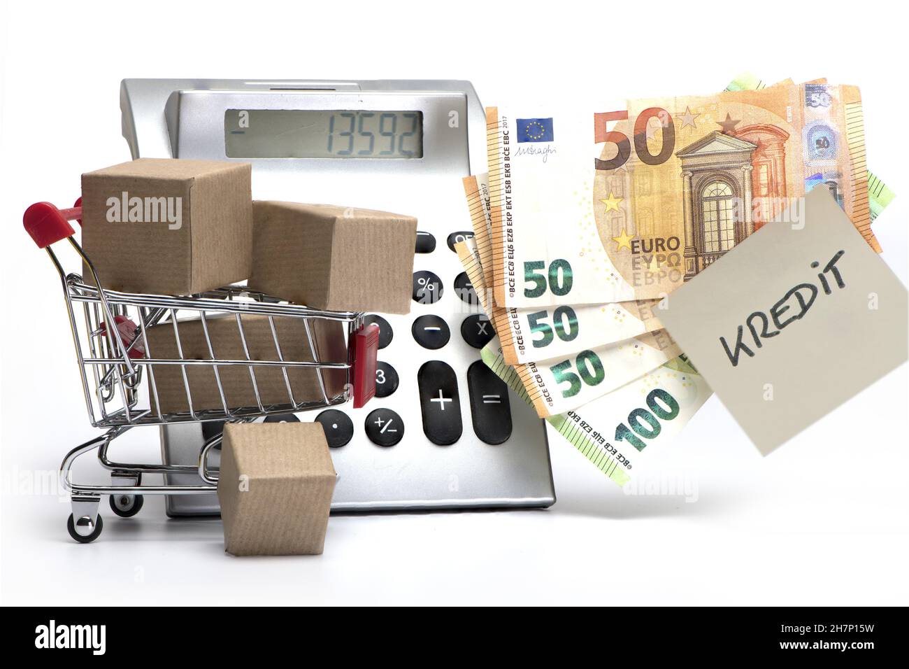 Calcolatrice che mostra debiti con pacchi e contanti e nota con iscrizione tedesca concetto di Kredit per debiti e indebitamento su sfondo bianco Foto Stock