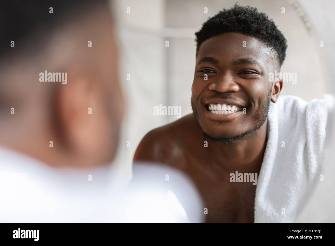 Guy Africano guardando Toothy Smile nello specchio in bagno Foto Stock