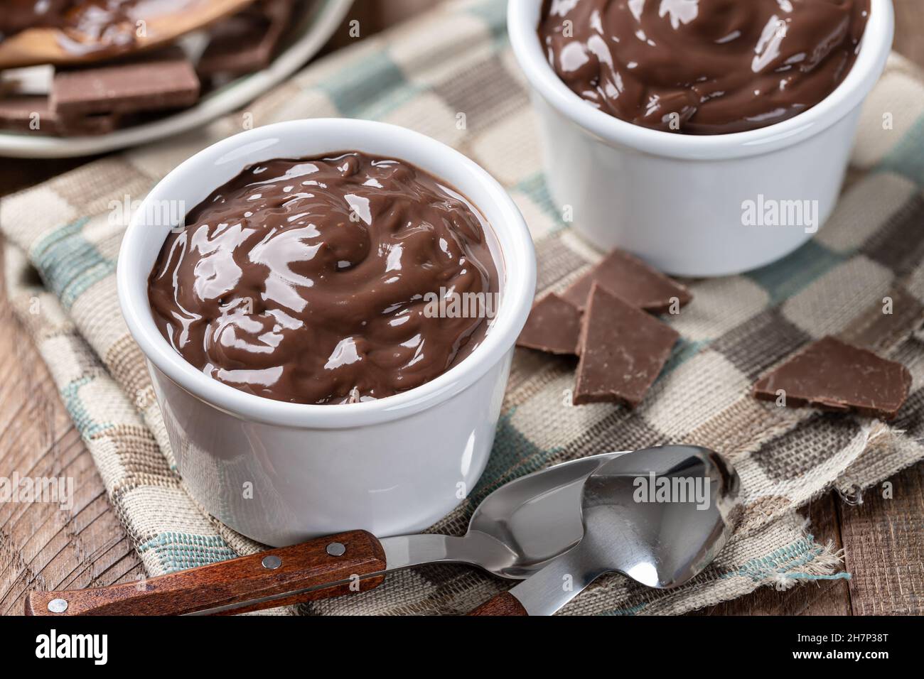 Primo piano di budino di cioccolato cremoso in una tazza bianca su un tovagliolo di stoffa Foto Stock