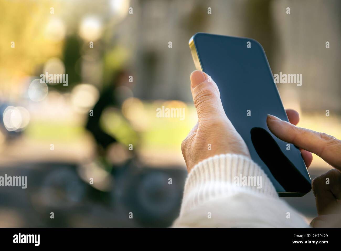 Mano della donna che tiene un cellulare e che fa un messaggio per strada Foto Stock