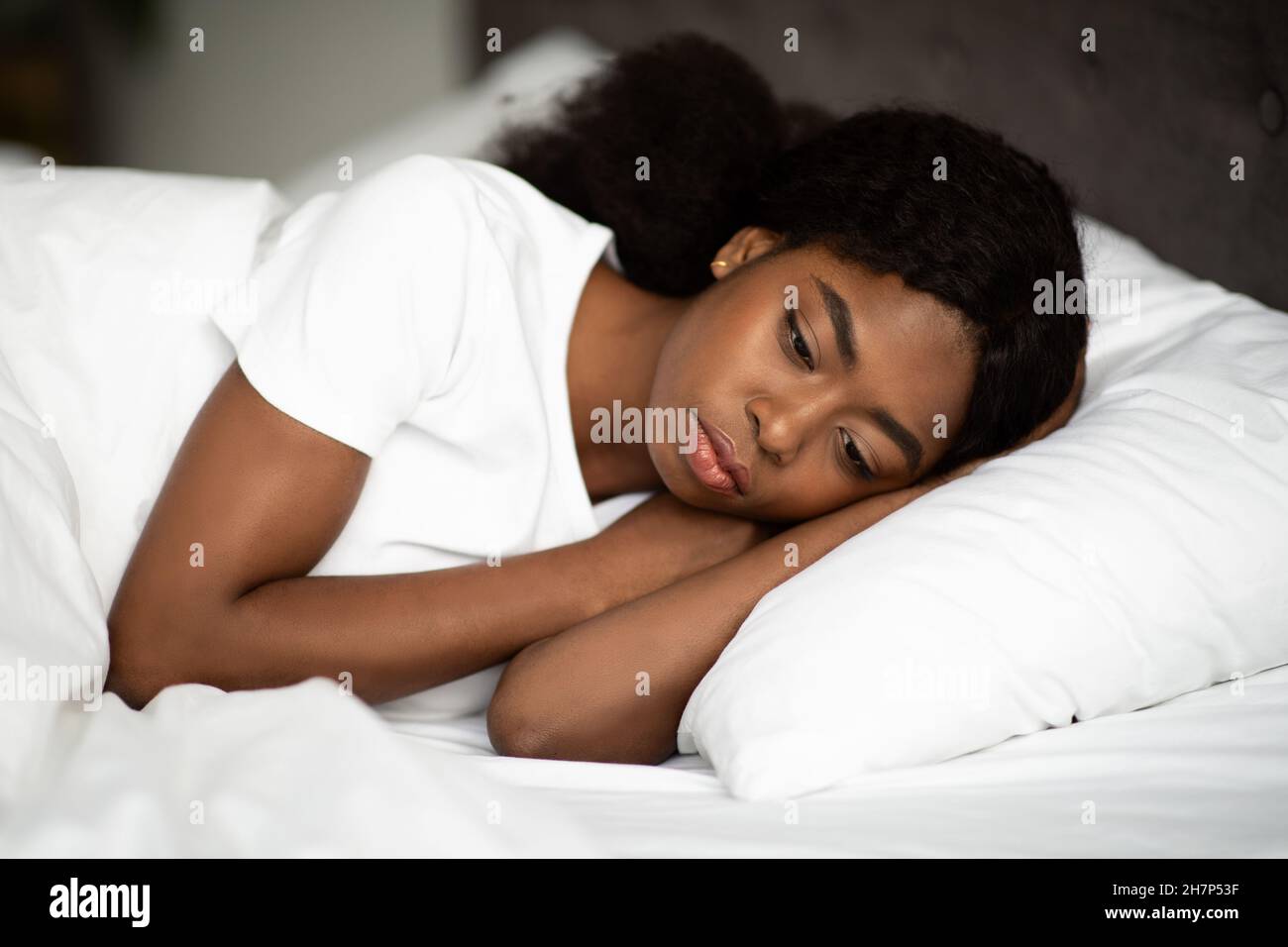 Turbata afroamericana signora che si stendendo a letto da solo Foto Stock