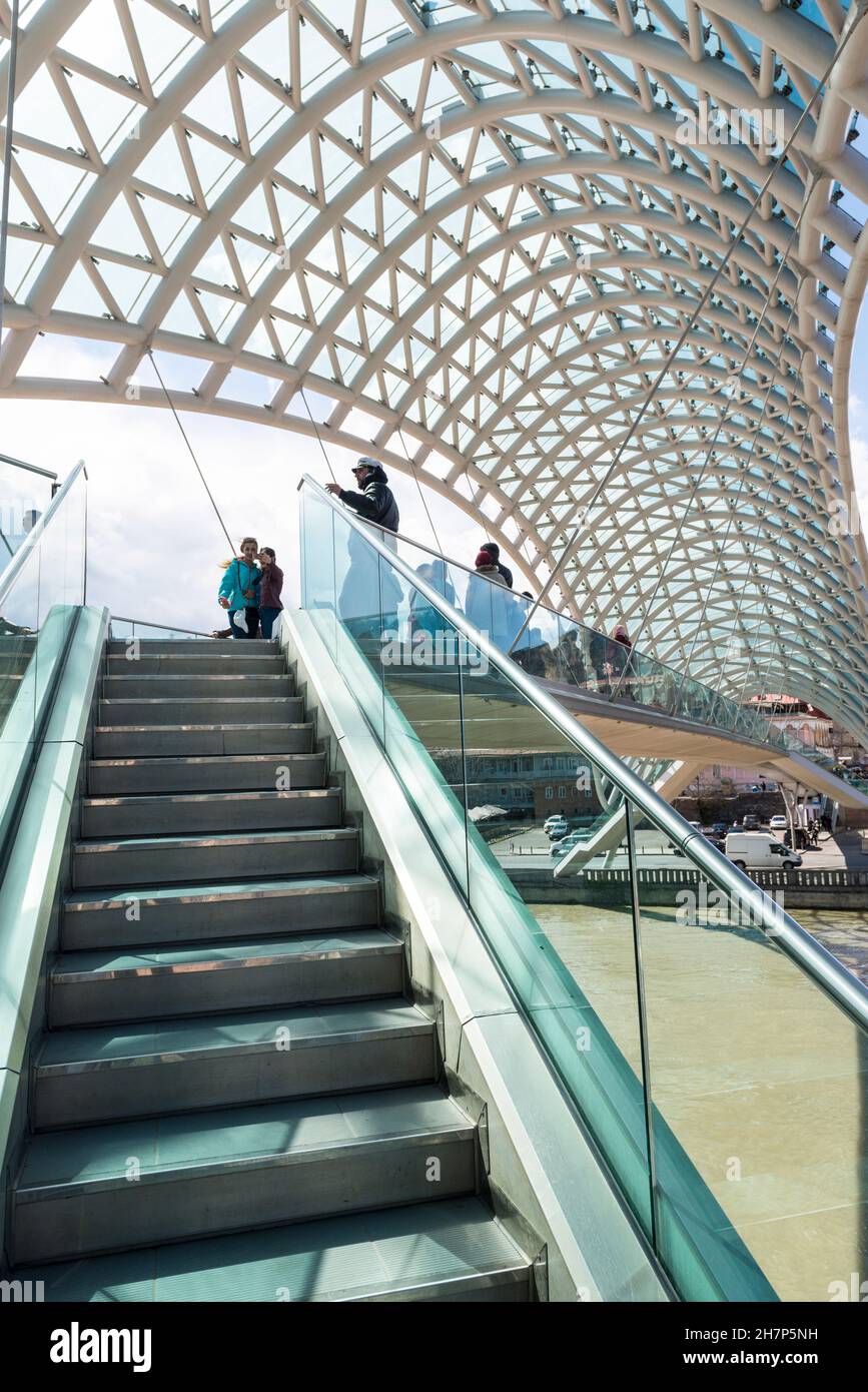Pedoni sull'iconico Ponte della Pace sul fiume Kura a Tbilisi, Georgia, Caucaso Foto Stock