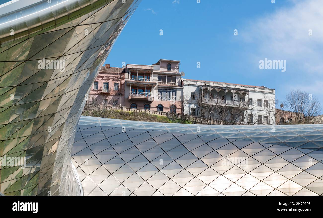 Vecchio e nuovo a Tblisi, Georgia: Case storiche viste sul moderno tetto in vetro e acciaio del centro esposizioni a forma di tubo e del teatro di musica Foto Stock