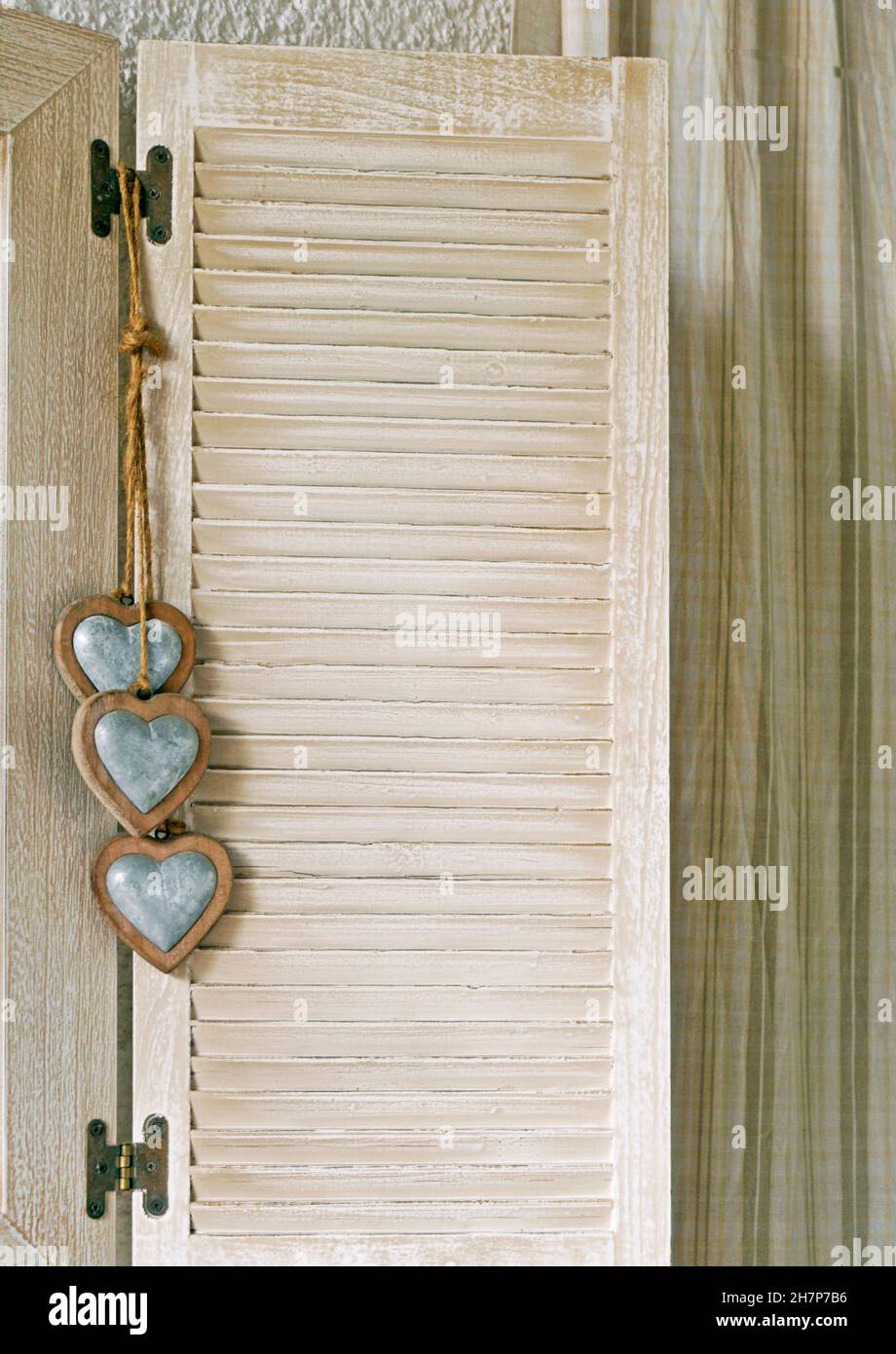 cuori decorativi shabby chic appesi sull'otturatore della finestra Foto Stock