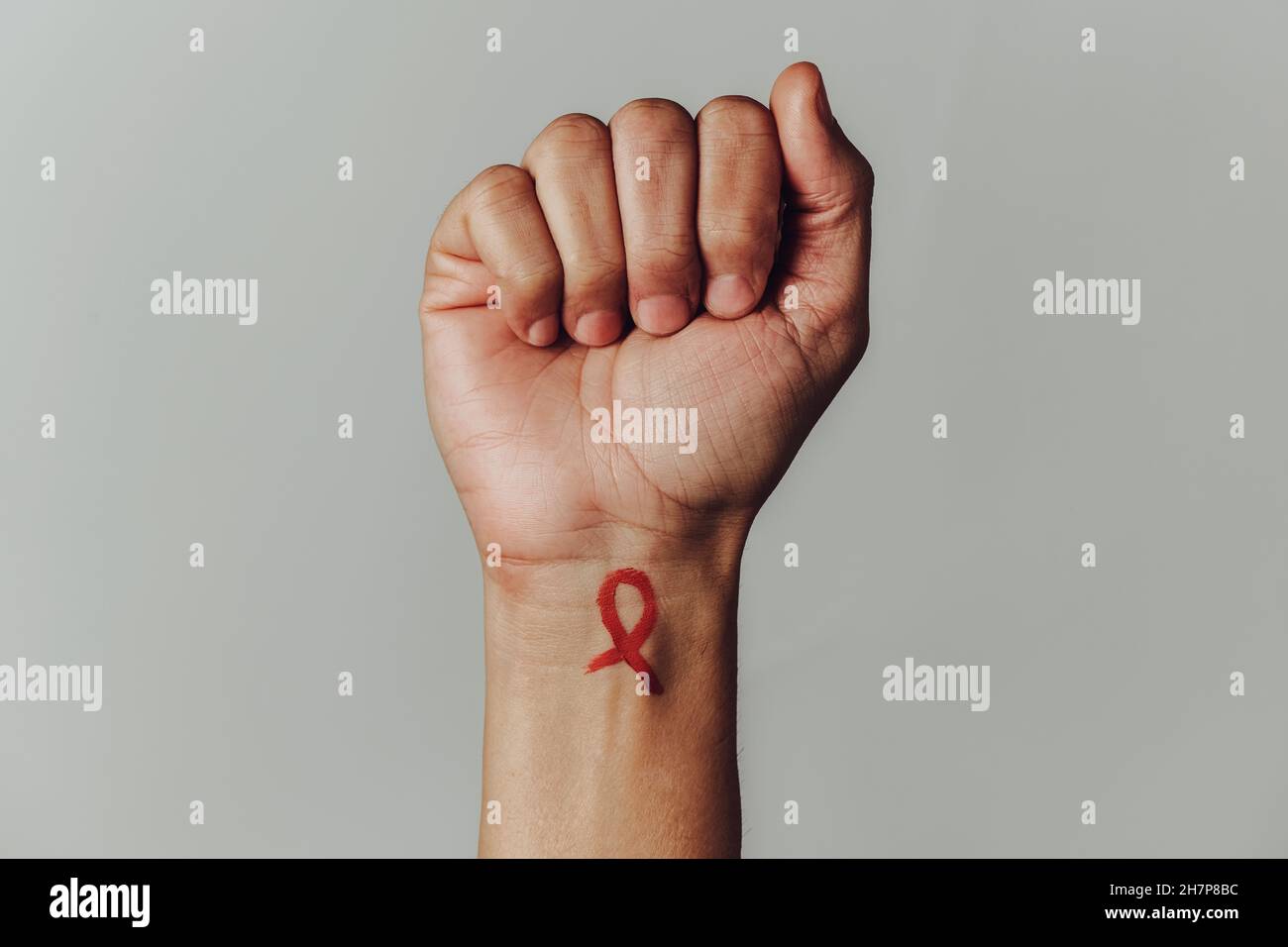 Il polso di un uomo con un nastro di consapevolezza rosso per la lotta contro l AIDS dipinto in esso su uno sfondo biancastro con uno spazio vuoto in un p Foto stock