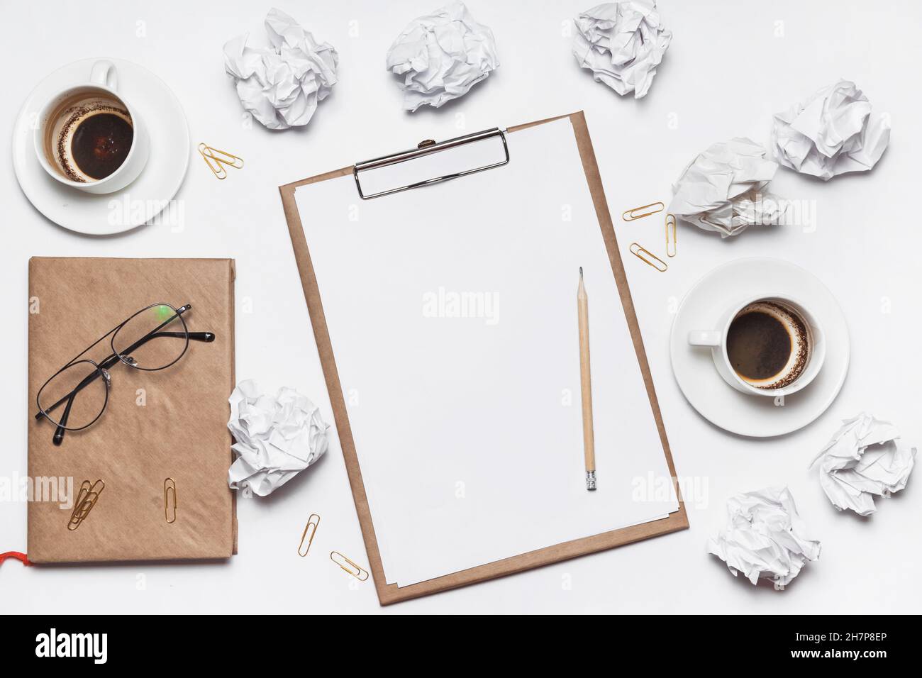 Carta sminuzzata sparsa, tazze vuote di caffè sul tavolo di un lavoratore creativo. Crisi creativa. Concetto di stress, problemi di salute mentale e mancanza di me Foto Stock