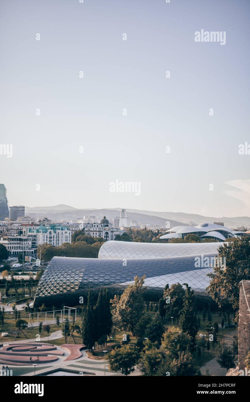Vista della città con edifici moderni e parco in Georgia. Parco d'arte moderna al tramonto. Nuova architettura in Europa. Tramonto spettacolare a Tbilisi. Foto Stock