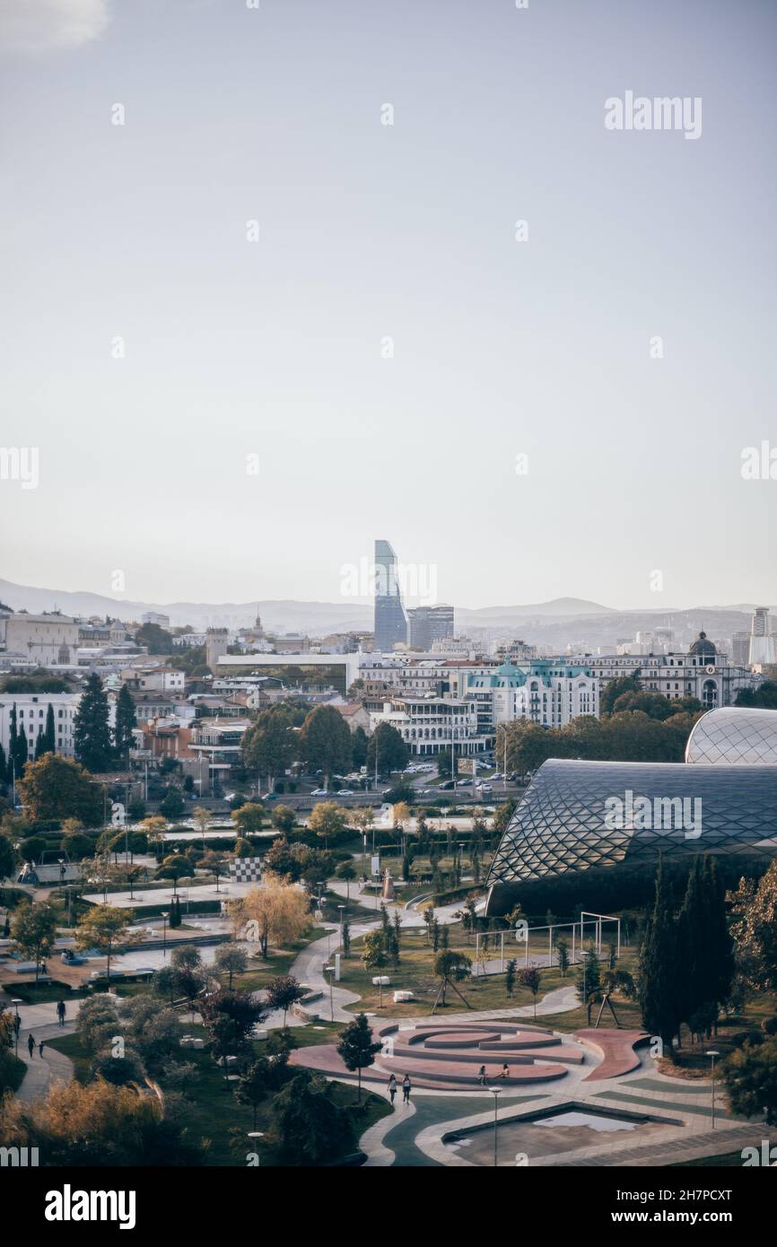 Vista della città con edifici moderni e parco in Georgia. Parco d'arte moderna al tramonto. Nuova architettura in Europa. Tramonto spettacolare a Tbilisi. Foto Stock