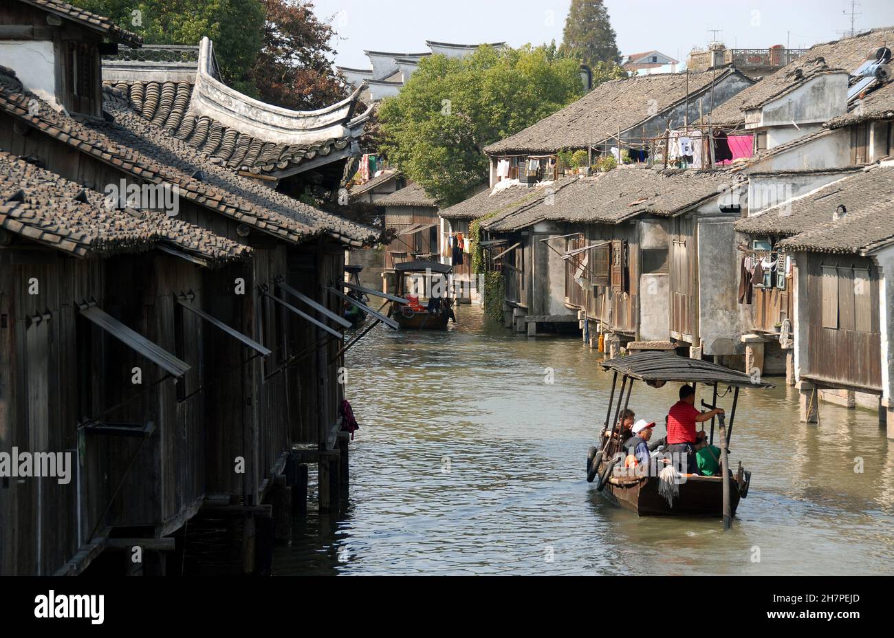 Wuzhen Water Town, Provincia di Zhejiang, Cina. Una piccola barca che trasporta i turisti esplora la città vecchia e i canali di Wuzhen. Persone irriconoscibili. Foto Stock