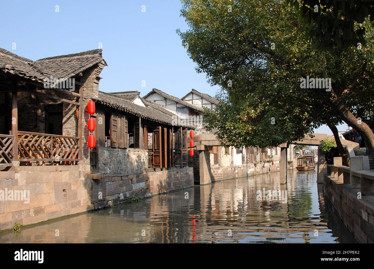 Wuzhen Water Town, Provincia di Zhejiang, Cina. Un tradizionale edificio in legno con lanterne rosse accanto ad un canale nella vecchia città cinese di Wuzhen. Foto Stock