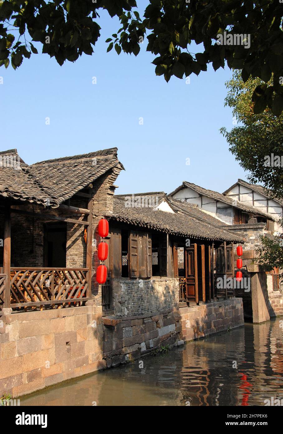 Wuzhen Water Town, Provincia di Zhejiang, Cina. Un tradizionale edificio in legno con lanterne rosse accanto ad un canale nella vecchia città cinese di Wuzhen. Foto Stock