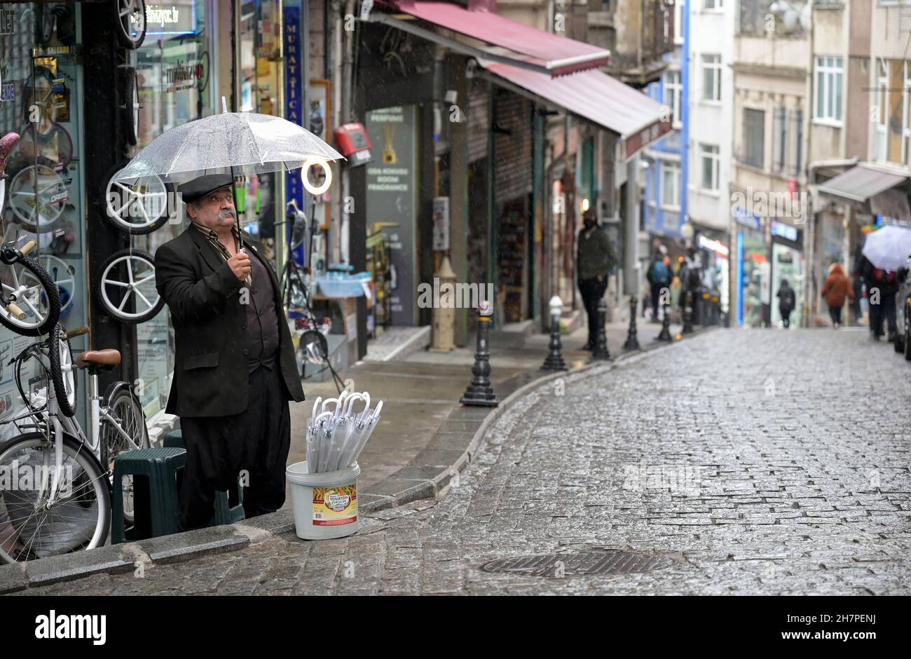 TURCHIA, Istanbul, Beyoglu, venditore di strada che vende ombrelloni durante la pioggia / Türkei, Istanbul, Stadtteil Beyoglu, Straßenverkäufer verkauft Regenschirme im Regen Foto Stock