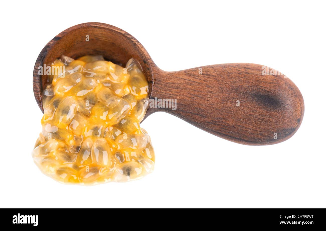 Semi di frutto della passione in cucchiaio di legno, isolato su sfondo bianco. Polpa di passionfrutto o maracuya, frutta esotica. Foto Stock