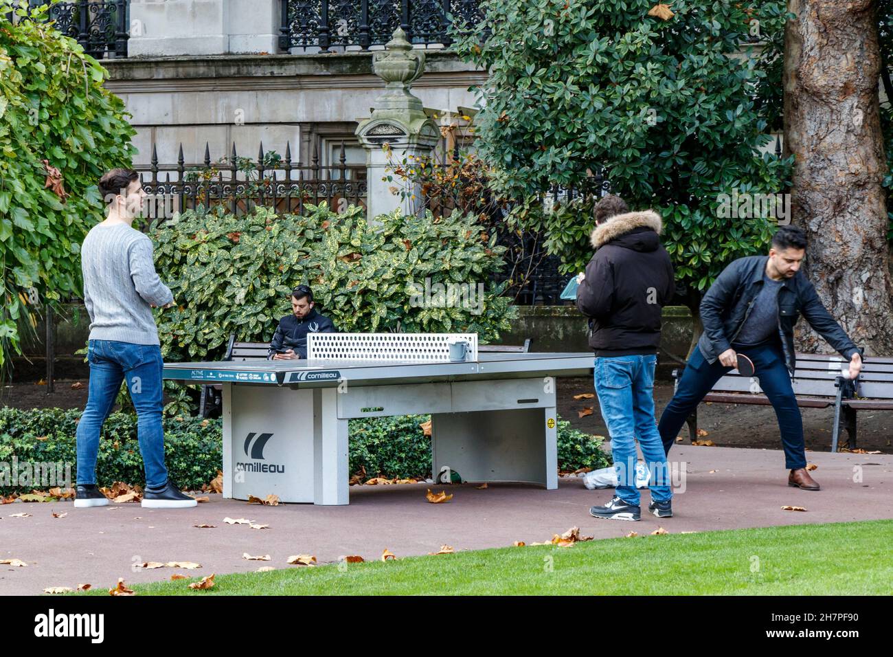 Giovani uomini che giocano a ping pong nella loro pausa pranzo a Whitehall Gardens, Victoria Embankment, Londra, Regno Unito Foto Stock