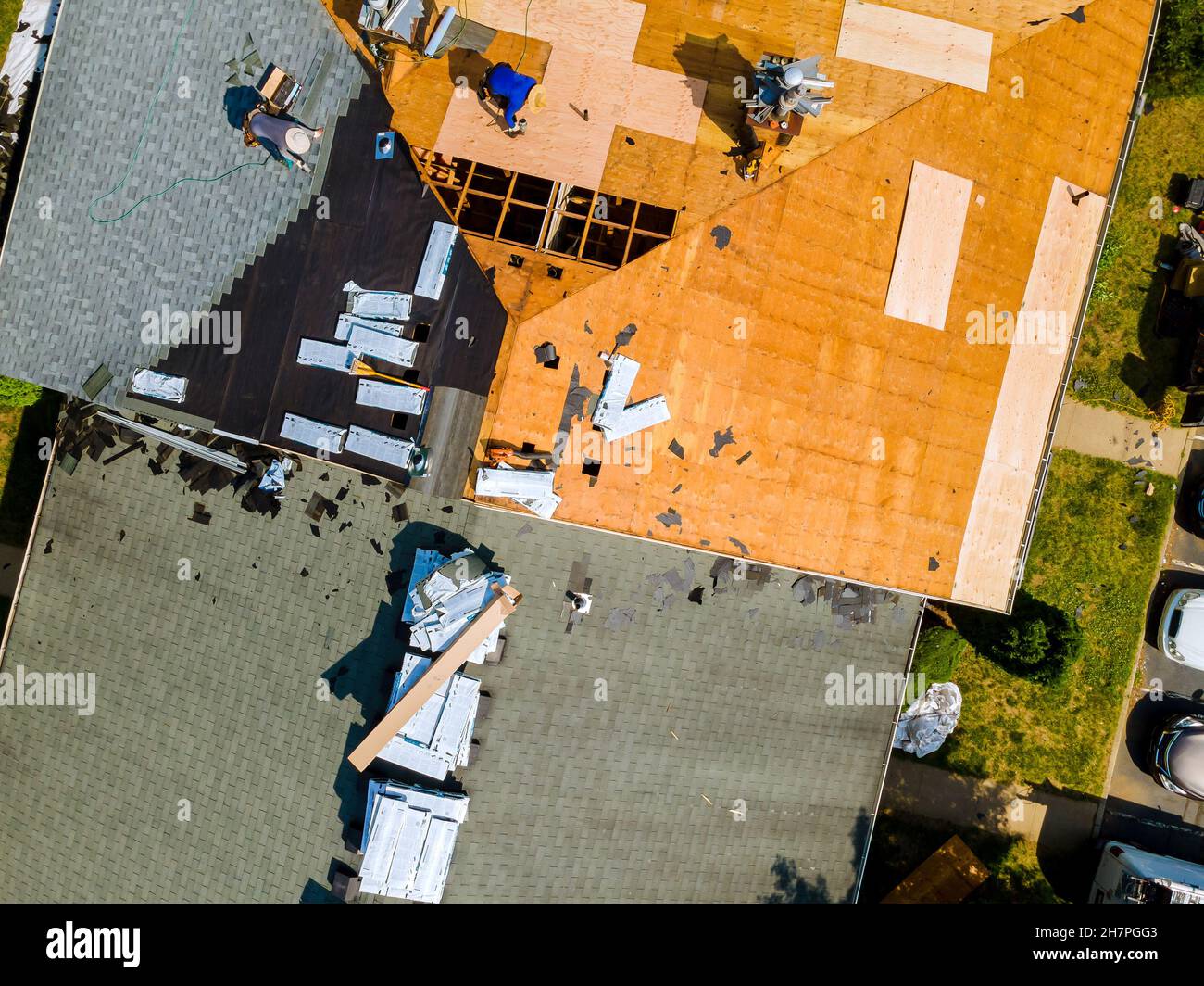 Un lavoratore sostituisce le cerniere sul tetto di una casa che ripara il tetto di casa Foto Stock