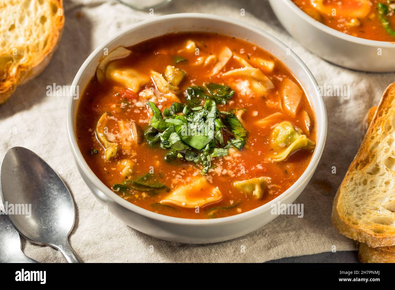 Zuppa italiana di tortellini fatta in casa con formaggio e basilico Foto Stock