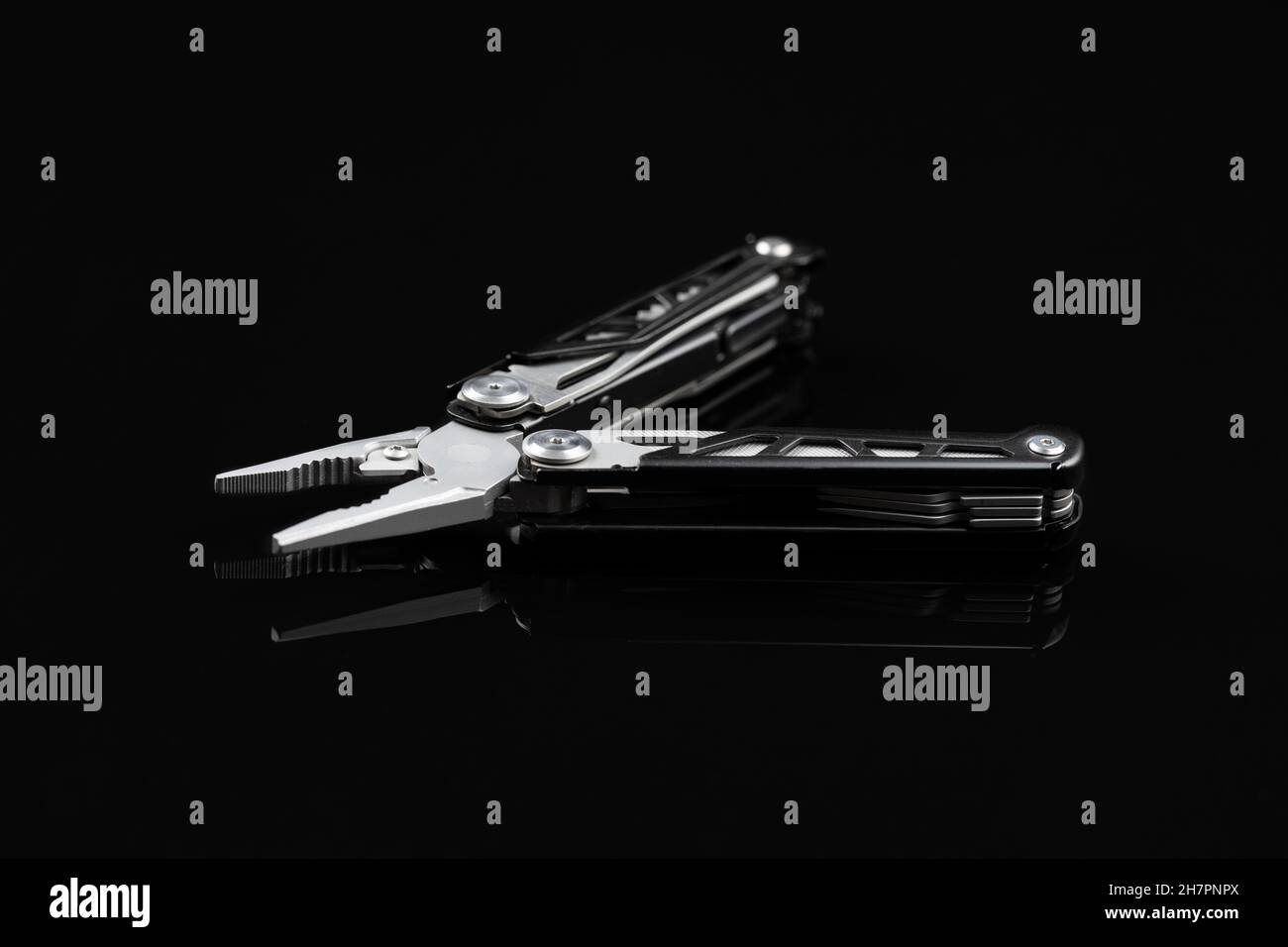 Pinza multiutensile con altri utensili e coltello. Pinza multifunzione su sfondo nero. Foto Stock