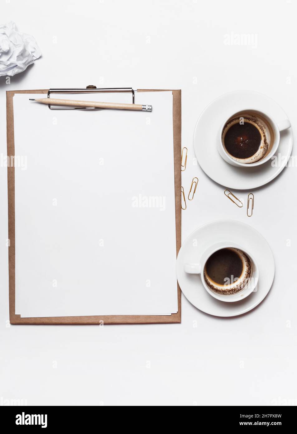 Carta sminuzzata sparsa, tazze vuote di caffè sul tavolo di un lavoratore creativo. Crisi creativa. Concetto di stress, problemi di salute mentale e mancanza di me Foto Stock