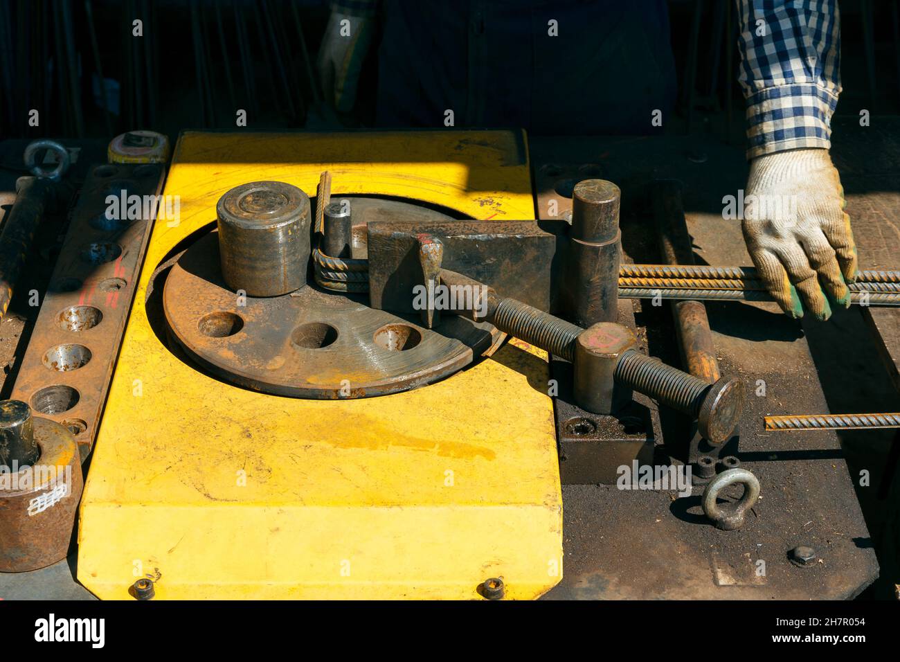 Le mani di un operatore al lavoro presso la macchina piegatrice di armature. Barrette con piegatrice in loco. Operatore che utilizza la macchina di armatura piegatrice per il reef Foto Stock