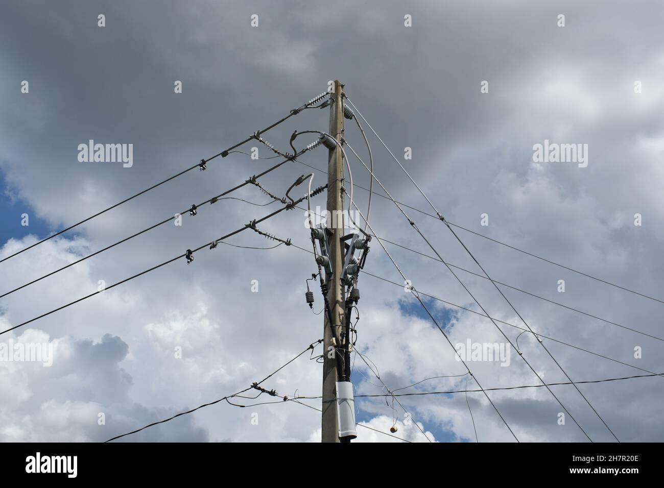 Le linee elettriche formano forme triangolari contro il cielo nuvoloso. Foto Stock