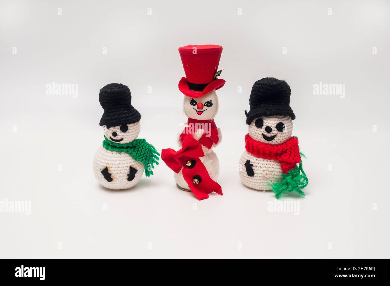Tre piccoli pupazzi di neve con un tema di Natale. Tutti hanno sciarpe e cappelli. Uno ha un cappello rosso, mentre gli altri due hanno un cappello nero. Foto Stock