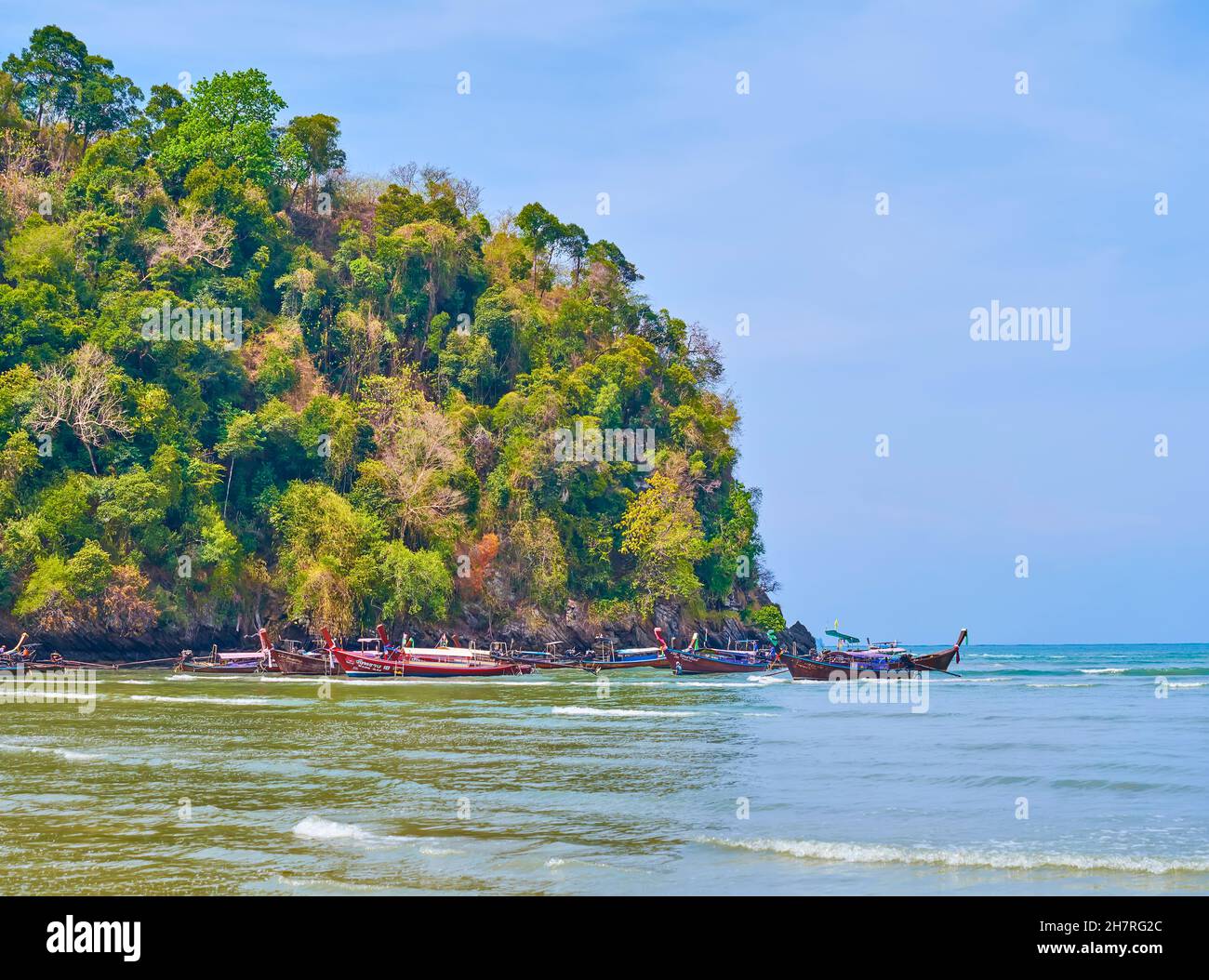 La vista sulla costa rocciosa della spiaggia di Ao Nang con barche a coda lunga ormeggiate, Krabi, Thailandia Foto Stock