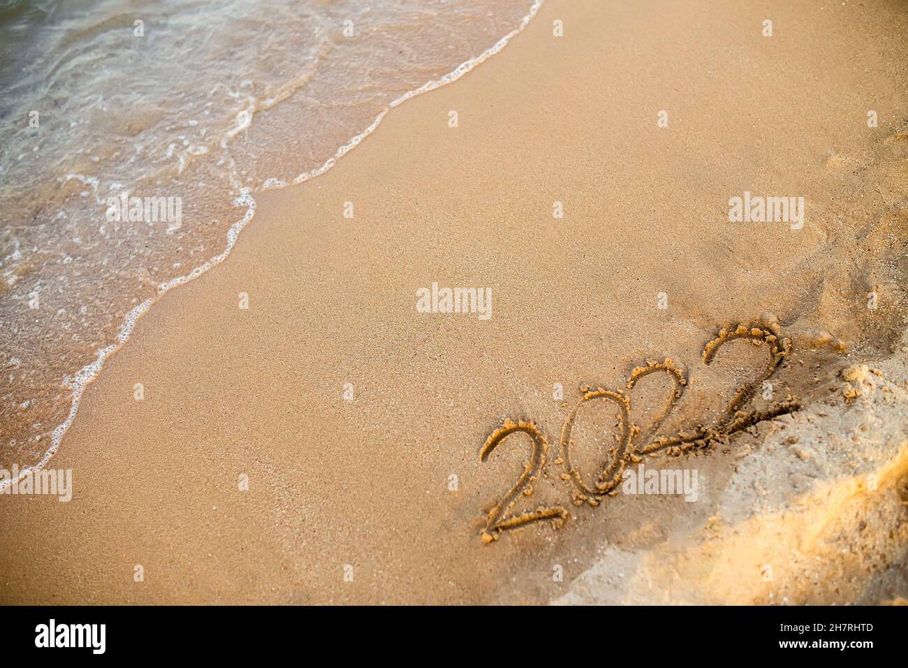 2022 numeri sono scritti sulla sabbia sulla spiaggia di mare. Il nuovo anno  2021 è in arrivo. Sfondo per banner o pubblicità di Capodanno Foto stock -  Alamy