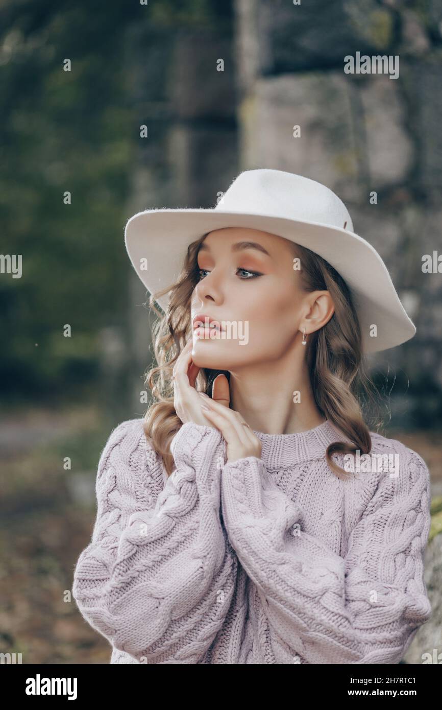 biondo in un cappello bianco cammina nel parco in un giorno d'autunno Foto Stock