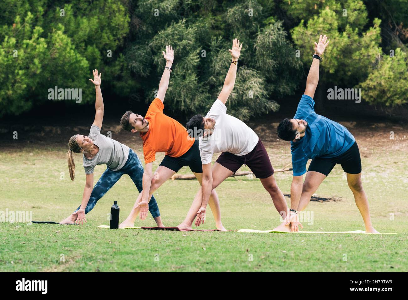Le persone che fanno la posa triangolare di yoga in un parco Foto Stock