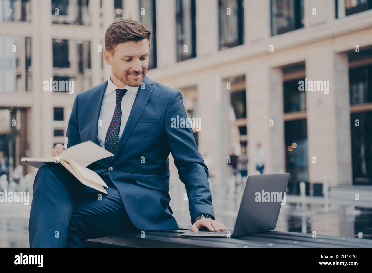 Giovane dipendente professionale che effettua ricerche sul notebook o guarda il webinar aziendale all'aperto Foto Stock