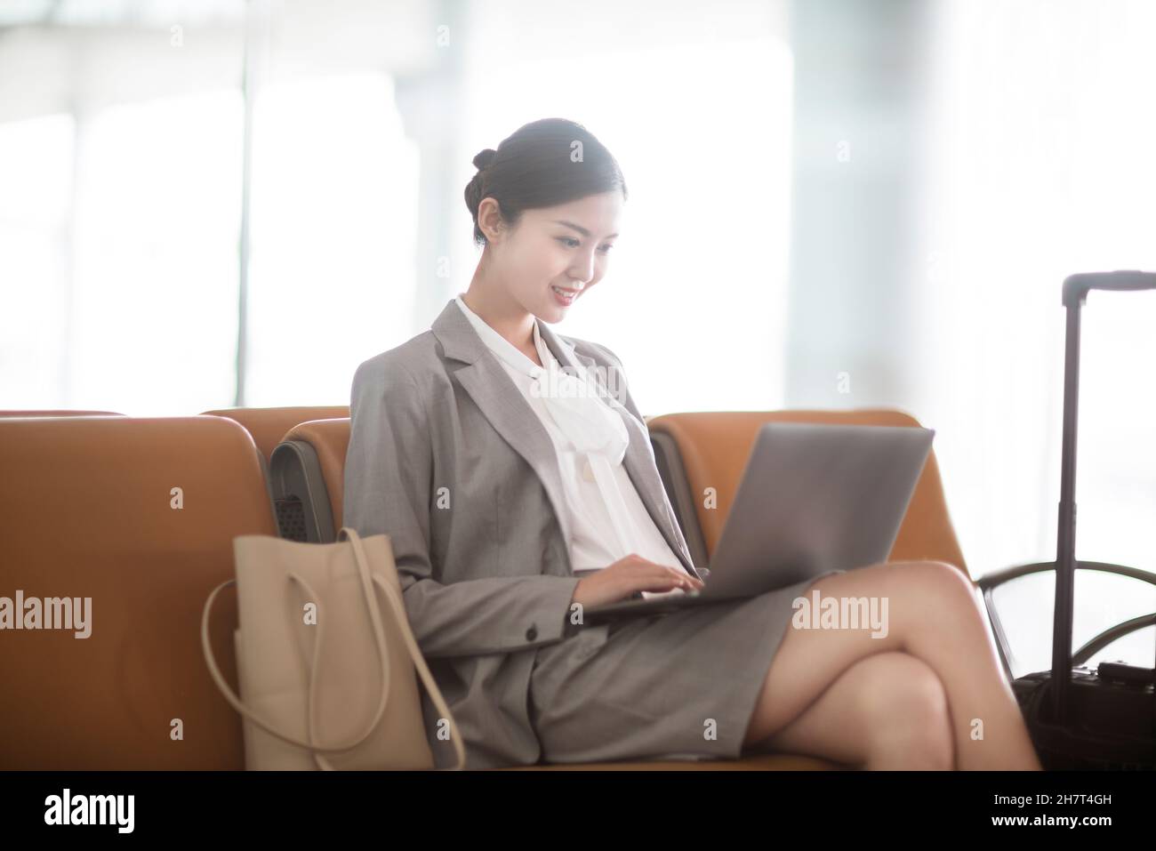 Giovane donna d'affari che usa un computer portatile nella sala d'attesa dell'aeroporto Foto Stock