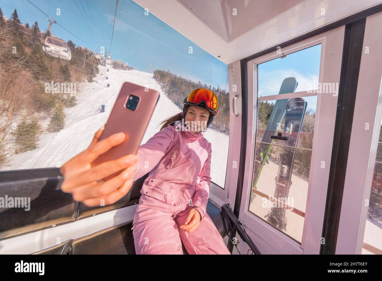Vacanza sci - sciatore donna in sciovia gondola facendo selfie foto o video con il telefono. Concetto di vacanze invernali sugli sci. Sciare sulle piste da neve in Foto Stock