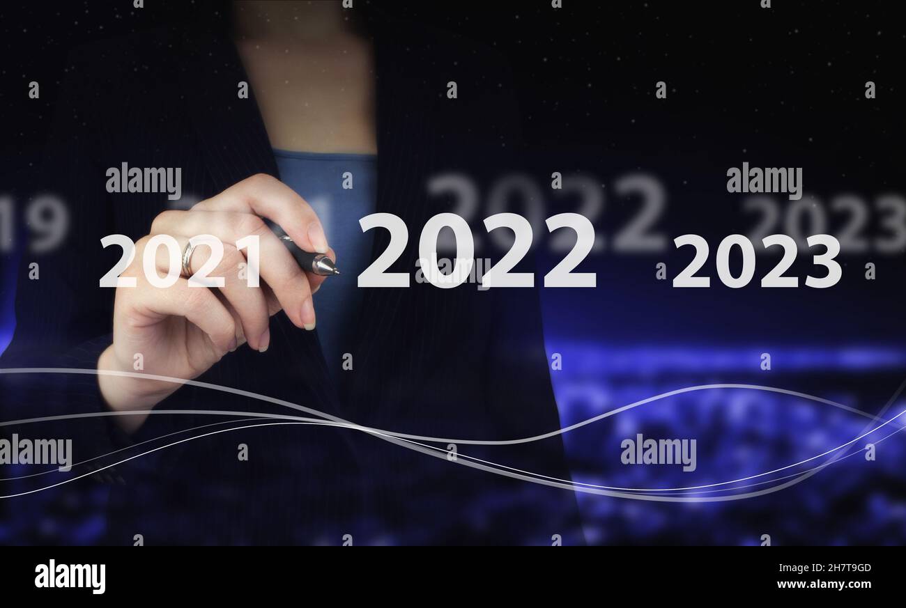 Anno di carico dal 2021 al 2022. Inizia concetto. Mano che tiene la penna grafica digitale e disegno ologramma digitale 2022 segno sulla città scuro sfocato. Concetto per vi Foto Stock