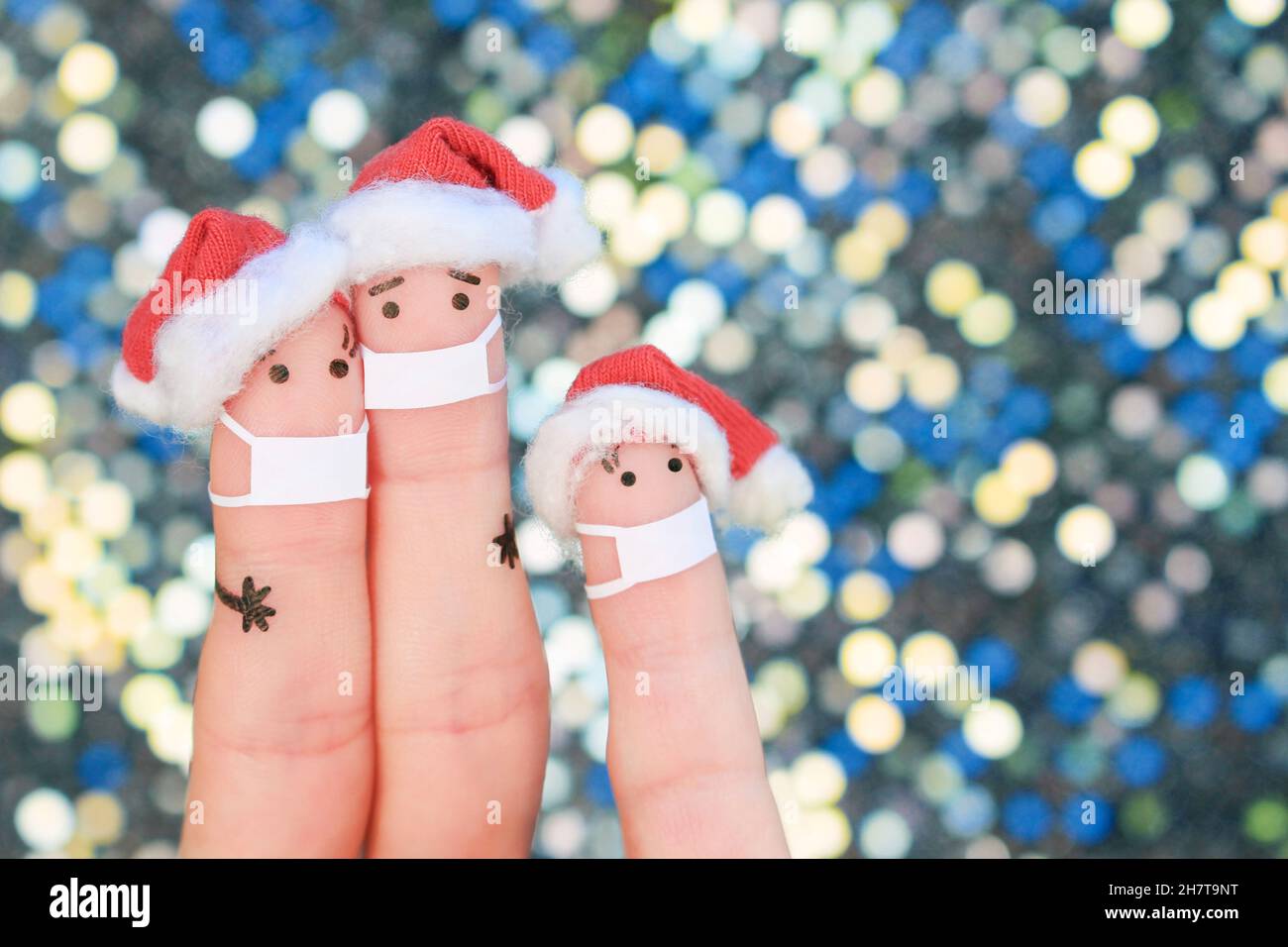 Fingers arte di famiglia in maschera medica da COVID-2019 celebra il Natale. Concetto di persone in cappelli di Capodanno. Foto Stock