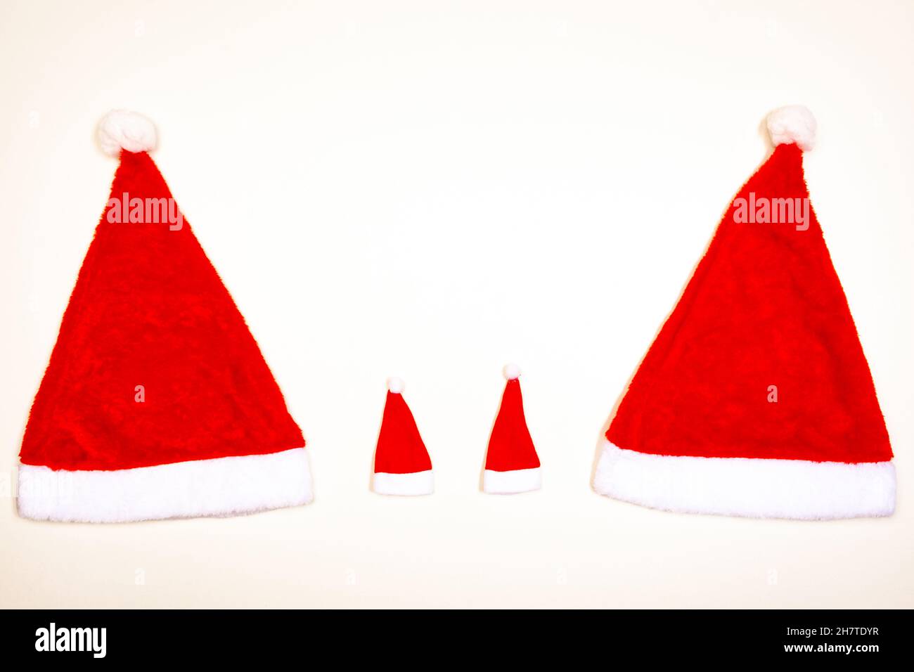 Due grandi e due piccoli cappelli di Natale su uno sfondo bianco, concetto, spazio di copia Foto Stock