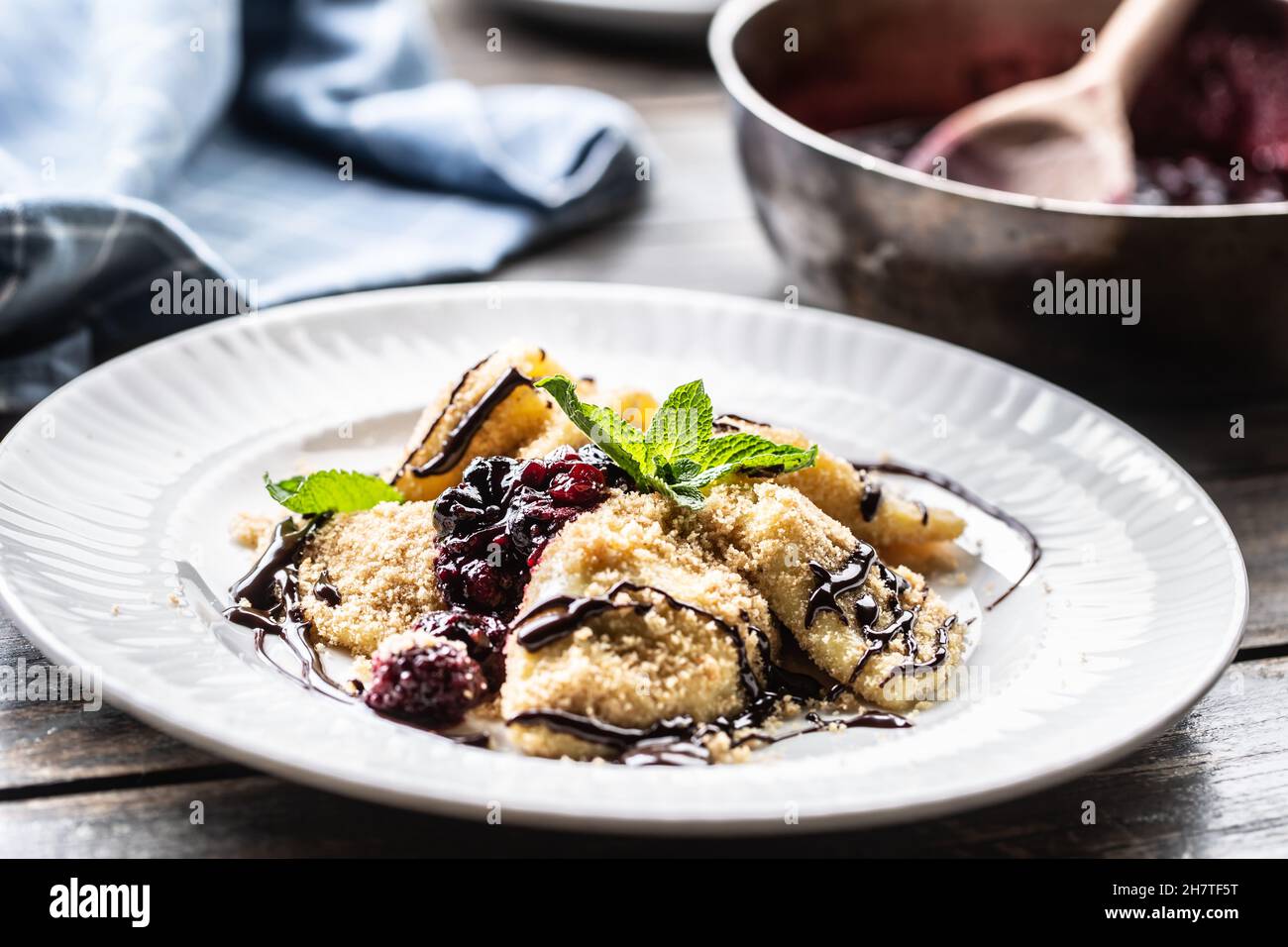 Pierogi appena fatti serviti con salsa di frutti di bosco e foglie di menta in cima. Foto Stock